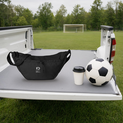 The FD Sling on a truck tailgate at a Saturday soccer game, next to a coffee and a ball, shown at true size